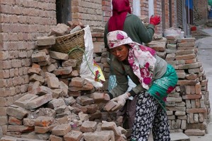 Due donne Newari appartenenti alla casta dei Sudra (i servi) lavorano come manovali caricando mattoni sulla grande cesta, chiamata "Doko", che isseranno sulla schiena aiutandosi a trasportare questo peso incredibile sulle scale dell'edificio dove stanno operando alla ricostruzione con una lunga fascia che porranno sulla fronte, villaggio di Kirtipur, Nepal 2018.