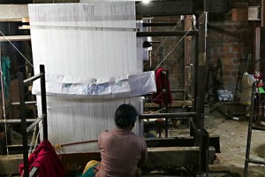 In un locale malsano per infiltrazioni d'acqua e umidità diffusa, un gruppo di donne Newari appartenenti alla casta dei "Sudra" (servi) lavora ai telai la lana ed altri filati: tradizionalmente il "mestiere" si tramanda di generazione in generazione e le tecniche sono le stesse da centinaia di anni. Villaggio di Khokana, Nepal 2018.