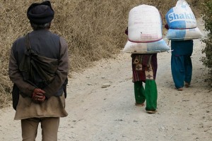 Un'istantanea che racchiude tutta la situazione profondamente discriminante delle donne in Nepal: due contadine Newari, di rientro dalla campagna dove hanno raccolto il frutto del loro lavoro, procedono piegate sotto il peso di enormi sacchi che portano sulla schiena per raggiungere il villaggio mentre, a poca distanza, le segue un uomo che cammina con le braccia dietro la schiena privo di qualsiasi fardello. Vicinanze del villaggio Khokanà, Nepal 2018.