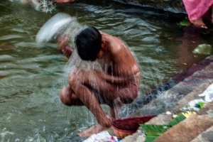 Nel Saundatti Lake, lago naturale sul quale si erge una enorme piscina con gradinate degradanti verso il basso, i pellegrini (prevalentemente donne, ma anche bambini), si bagnano, lavano le vesti, abbandonano le cose vecchie, lasciano offerte alla Dea Yallamma: qui un bambino si sta bagnando versando l'acqua mediante una piccola anfora in metallo argentato. Dintorni del villaggio di Saundatti, Regione del Karnataka, India 2015.