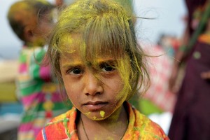 Anche i bambini partecipano alla Festa in onore della Dea Yallamma: anche loro sono ricoperti della polvere ocra di curcuma e rossa di kum kum, tra nuvole gialle e rosse che si addensano nell'aria ad ogni lancio da parte dei pellegrini festanti. Questa bimba dallo sguardo intenso e quasi corrucciato si chiama "Shaila" (figlia della collina). Dintorni del villaggio di Saundatti, Regione del Karnataka, India 2015.