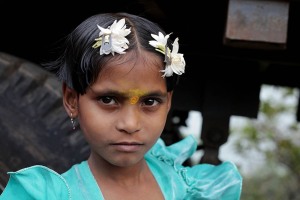 Avani, una bambina Hindu nel grande accampamento alle porte del villaggio di Saundatti che accoglie i pellegrini (oltre centomila) giunti si qui per festeggiare la Dea Yallamma durante il Renuka Yallamma Jatra: dietro di lei il camion con cui ha percorso, insieme alla sua famiglia, le centinaia di chilometri di distanza che dividono il suo villaggio da Saundatti. Regione del Karnataka, India 2015.