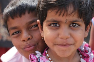 I bambini indiani, come un po' in tutto il mondo, sono quasi sempre sorridenti, gentili e disposti a farsi fotografare: qui Gyanada, la bambina in primo piano, è insieme al fratello più grande, Ajitabh. Poco distanti vi sono i genitori che li hanno portati alla grande festa in onore della Dea Yallamma. Villaggio di Saundatti, regione del Karnataka, India 2015.