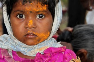 Chitragandha, una bambina Hindu presente al Renuka Yallamma Jatra (i festeggiamenti in onore della Dea Yallamma), tra la confusione che precede il pasto organizzato dalla sua famiglia allargata, è la prima a mangiare il "Prasad", cioè il cibo offerto alla Divinità  che, pertanto a seguito di tale rito, è divenuto sacro e benedetto. Dintorni del villaggio di Saundatti, regione del Karnataka, India 2015.