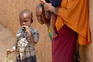 Bambina Houssa mi scruta sporgendosi dall'uscio della sua abitazione in fango e paglia, Villaggio D'Aoudarass, Niger 2020