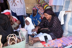 Sguardo stizzito, Mercato di Iferouane, donne Haoussa propongono le loro mercanzie mentre la bambina al centro mi saluta con il dorso della mano rivolta verso di me simboleggiando "vai al diavolo", Festival dell'Air, Deserto del Ténéré, Regione dell'Air, Niger 2020