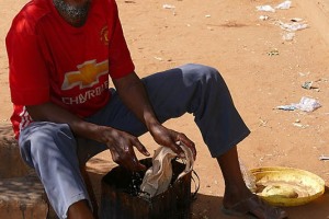 Uomo appartenente all'etnia Haoussa sciacqua uno straccio in un secchio con dell'acqua utilizzato nella sua bottega di artigiano, Cooperativa Artigianale del Museo nazionale boubou Hama, Museo Nazionale Etnografico di Niamey, Niger 2020