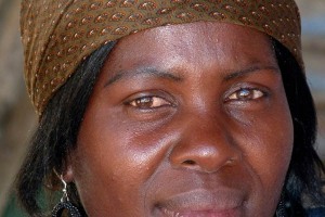 Giovane e affascinante donna appartenente al Popolo Xhosa, il secondo maggior gruppo etnico del Sud Africa dopo gli Zulu. Lo stesso Nelson Mandela era uno Xhosa, il "Popolo rosso" come solitamente viene definito a causa degli abiti di colore rosso che indossano prevalentemente. L'abbigliamento per loro ha un "codice" abbastanza complesso: il rosso e l'arancione sono i colori base che vengono solitamente utilizzati, ma il loro modo di vestire può cambiare in base alla posizione sociale ed in base alla fase della loro vita. Le donne sposate, ad esempio, indossano una specie di turbante intrecciato colorato, con stili differenti a seconda di chi lo indossa: una ragazza appena sposata avrà un copricapo differente da quello di una donna che ha messo al mondo il primo figlio. Gli abiti vengono decorati ed impreziositi da complesse lavorazioni realizzate con perline colorate, perle di vetro, semi, gusci ed altri materiali naturali che rendono questi capi dei veri e propri capolavori.Villaggio Lesedi, Sud Africa 2012